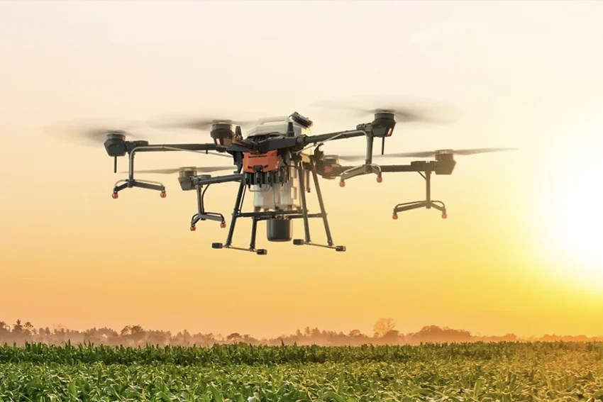 Drone de pulvérisation agricole au-dessus d'une parcelle au coucher du soleil
